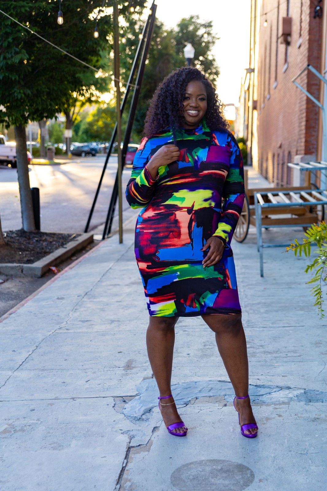 Shonte smiling in a colorful dress on a downtown sidewalk